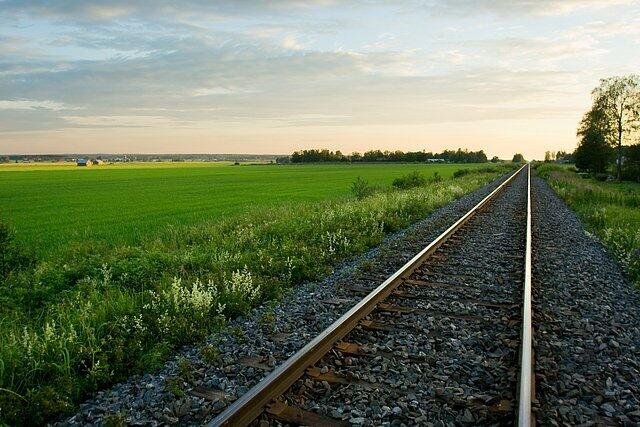 Kuvassa on kesäinen peltomaisema ja junarata