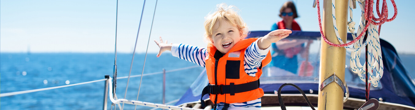 pieni poika veneen kannella pelastusliivit päälläl