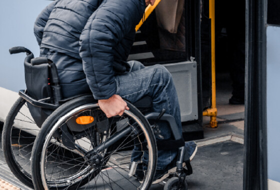 Henkilö menee pyörätuolilla bussiin