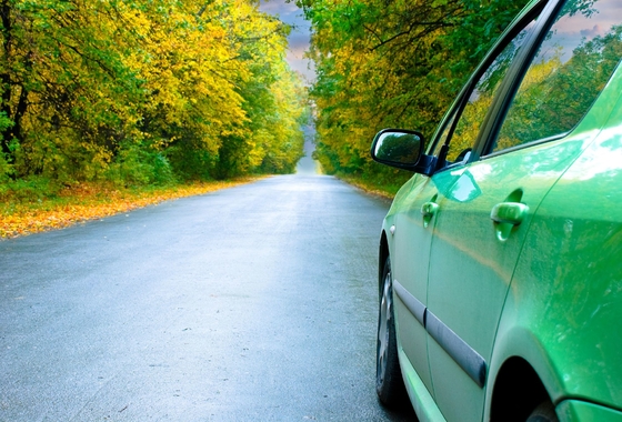 vihreä henkilöauto syksyisellä tiellä