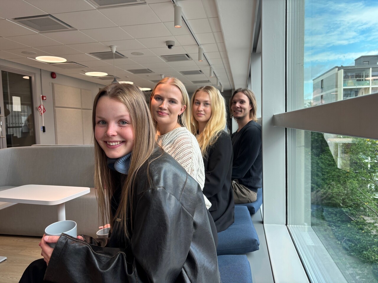  Neljä työntekijää istumassa ja hymyilemässä kameralle