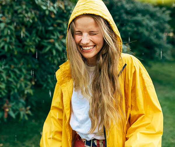Nainen kävelee sateessa keltainen sadetakki päällä